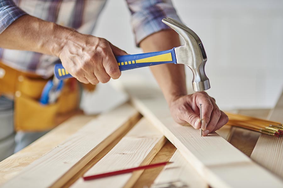 Specialized Business Insurance - Hands Holding a Hammer and Nail, Constructing Using Planks of Wood